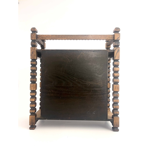 250 - An Arts and Crafts oak smoker's compendium, circa 1910, carved frame, single door with turquoise cab... 