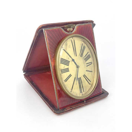 277 - An easel travel timepiece, early 20th Century, red leather outer case, oval gilt dial with Roman num... 