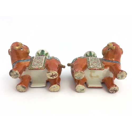 442 - A pair of 19th Century Canton famille rose standing elephant candle holders, looking to the right an... 