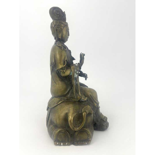 452 - A cast bronze figure of Guan Yin, modelled seated on a recumbent elephant, impressed seal mark, 28cm... 