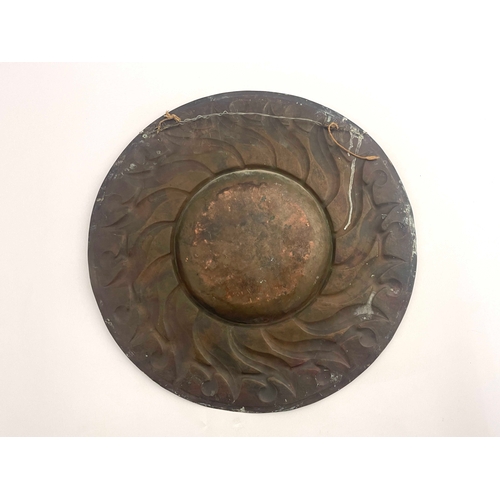 523 - An Arts and Crafts copper charger, probably Newlyn, broad rimmed, decorated with lappet and wreath d... 