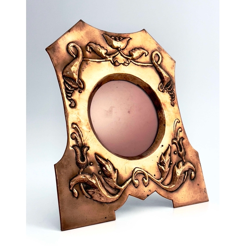 524 - An Arts and Crafts copper photo frame, shaped bracket form, embossed with upturned cornucopia, knott... 