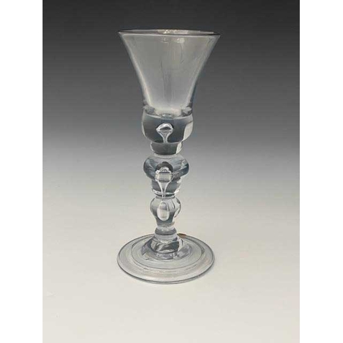 557 - An acorn knopped baluster wine glass, circa 1720, the flared bell shaped bowl with teardrop inclusio... 