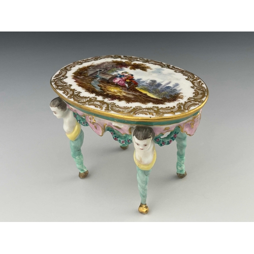 643 - A 19th century Dresden porcelain model table, the oval top painted with a Watteau type scene of a co... 