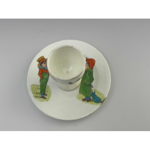 718 - Kate Greenaway for Collingwood, a nursery egg cup and integrated stand, circa 1890s, transfer printe... 