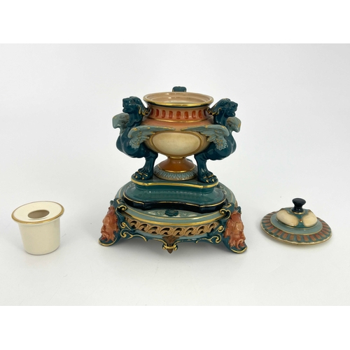 774 - A Hadleys Worcester inkwell, reticulated and relief moulded, the pedestal urn supported on three tra... 