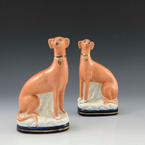 831 - A pair of Staffordshire flatback chimney greyhounds, 19th Century, modelled seated wearing gilt coll... 