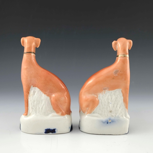 831 - A pair of Staffordshire flatback chimney greyhounds, 19th Century, modelled seated wearing gilt coll... 