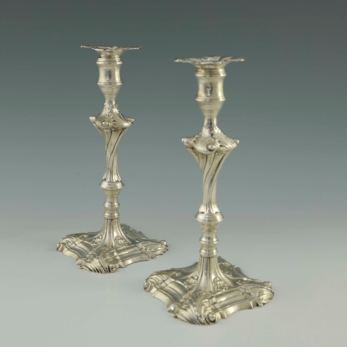 49 - A pair of George III cast silver candlesticks, Ebenezer Coker, London 1762, ogee fluted square bases... 