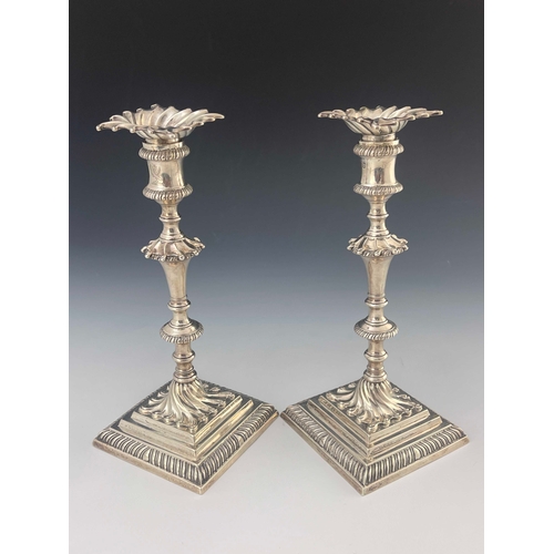 56 - A pair of George III cast silver candlesticks, Ebenezer Coker, London 1770, stepped square section b... 