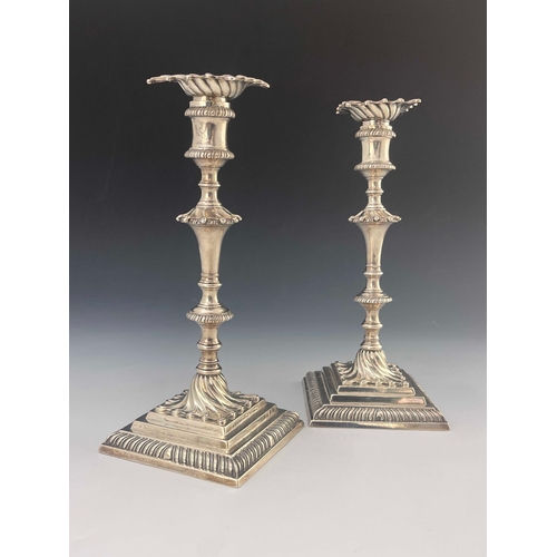 56 - A pair of George III cast silver candlesticks, Ebenezer Coker, London 1770, stepped square section b... 