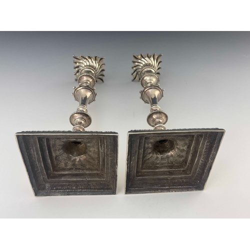 56 - A pair of George III cast silver candlesticks, Ebenezer Coker, London 1770, stepped square section b... 