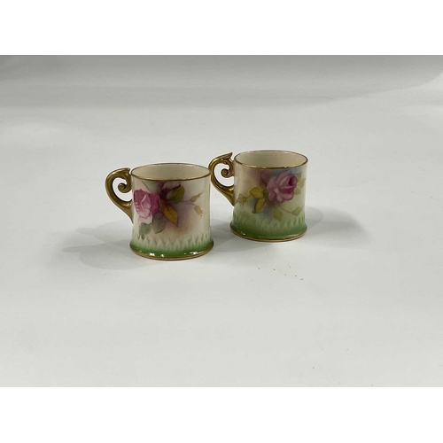 145E - Two Royal Worcester rose painted miniature mugs, circa 1920, cylindrical form with gilded scroll han... 