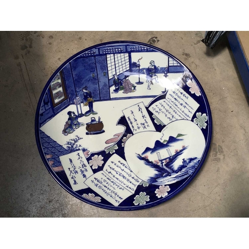 159 - A late 19th Century Japanese large blue and white circular charger, painted with figures in domestic... 