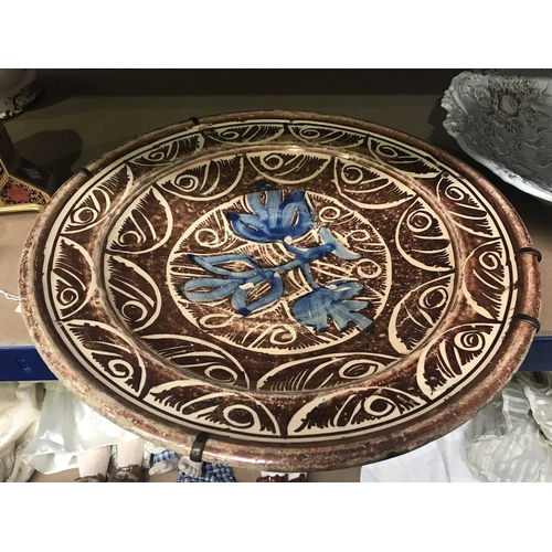 161B - An Hispano Moresque terracotta copper lustre plate, decorated with blue leaves within central patter... 