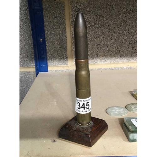 345 - A large calibre bullet shell, mounted on wooden stand