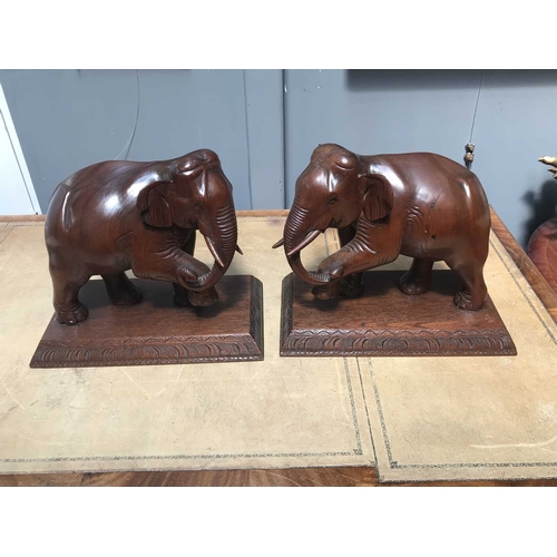 421 - A pair of Burmese decorative ornamental hardwood models of elephants, each strolling with raised tru... 