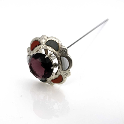 7 - A silver and Scottish hardstone set thistle hat pin, the central amethyst within a chased frame of s... 