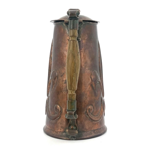 155 - An Arts and Crafts copper lidded jug, repousse embossed with fleur de lys motifs to each side, rivet... 