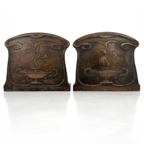 157 - A pair of Arts and Crafts copper bookends, repousse embossed and planished with stylised Roman oil l... 