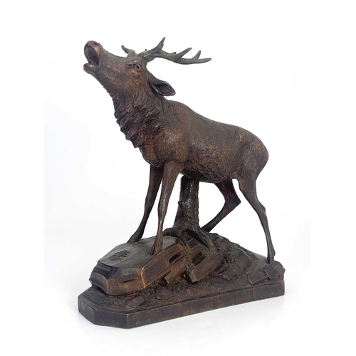 216 - A Black Forest carved wooden model of a stag, standing on a rocky outcrop with head raised, five-poi... 