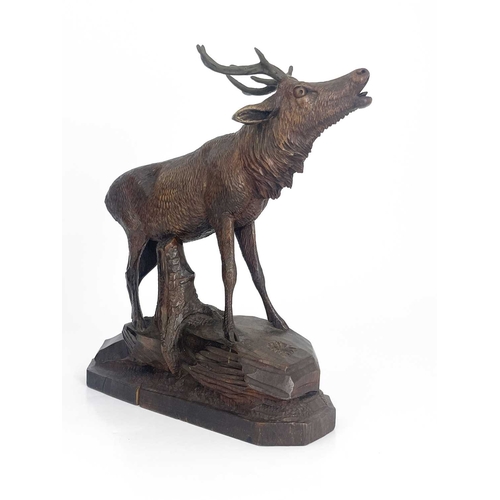 216 - A Black Forest carved wooden model of a stag, standing on a rocky outcrop with head raised, five-poi... 