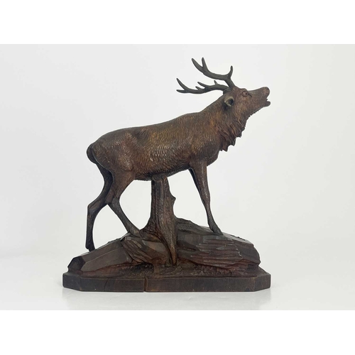 216 - A Black Forest carved wooden model of a stag, standing on a rocky outcrop with head raised, five-poi... 