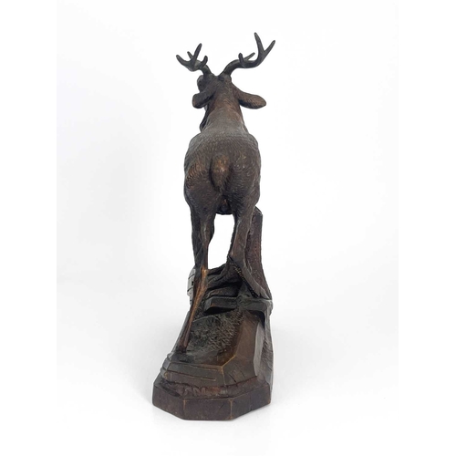 216 - A Black Forest carved wooden model of a stag, standing on a rocky outcrop with head raised, five-poi... 