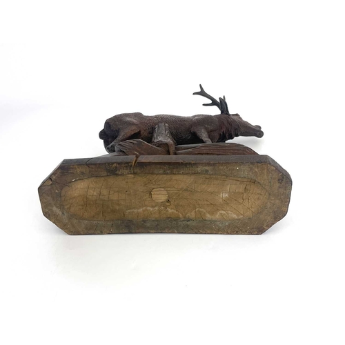 216 - A Black Forest carved wooden model of a stag, standing on a rocky outcrop with head raised, five-poi... 