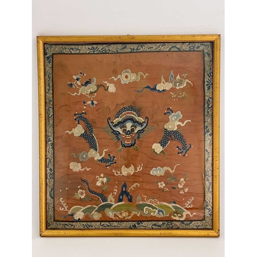 490 - A Chinese silk embroidered panel, decorated with dragon amongst clouds, on rust coloured ground, 65c... 