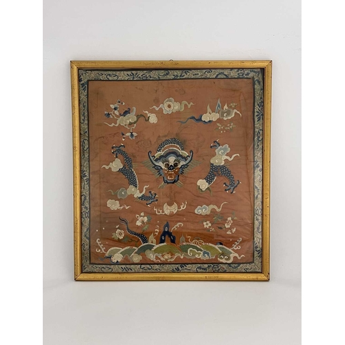 490 - A Chinese silk embroidered panel, decorated with dragon amongst clouds, on rust coloured ground, 65c... 