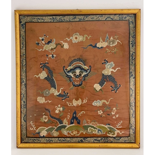 490 - A Chinese silk embroidered panel, decorated with dragon amongst clouds, on rust coloured ground, 65c... 