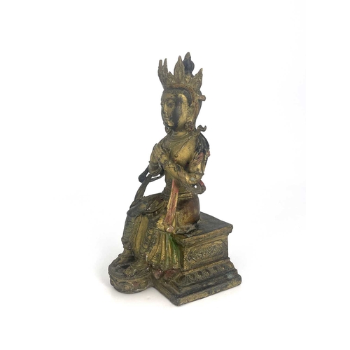 509 - An Oriental gilt bronze figure of Tara, modelled sitting on a plinth, highlighted in polychrome enam... 