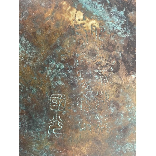 511 - A Chinese bronze plate, scalloped rim, cast in relief with a triple clawed dragon chasing a flaming ... 