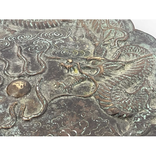 511 - A Chinese bronze plate, scalloped rim, cast in relief with a triple clawed dragon chasing a flaming ... 