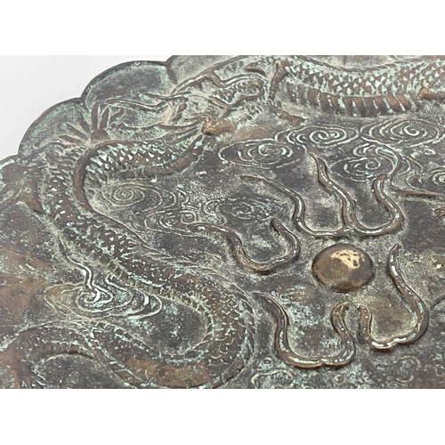 511 - A Chinese bronze plate, scalloped rim, cast in relief with a triple clawed dragon chasing a flaming ... 