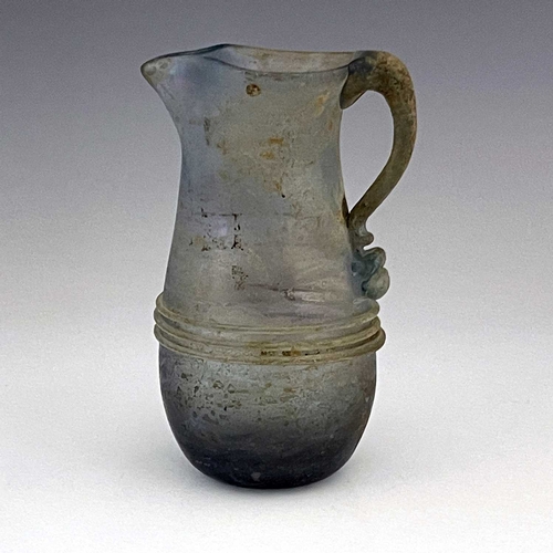 514 - A Roman glass jug, probably late Imperial, baluster form with applied trailing and loop handle, 16cm... 