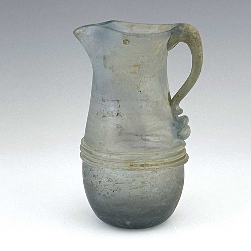 514 - A Roman glass jug, probably late Imperial, baluster form with applied trailing and loop handle, 16cm... 