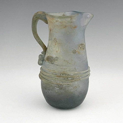 514 - A Roman glass jug, probably late Imperial, baluster form with applied trailing and loop handle, 16cm... 