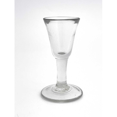 524 - A plain stemmed toasting glass, circa 1740, the heavy bell shaped bowl on a short stem and thick foo... 