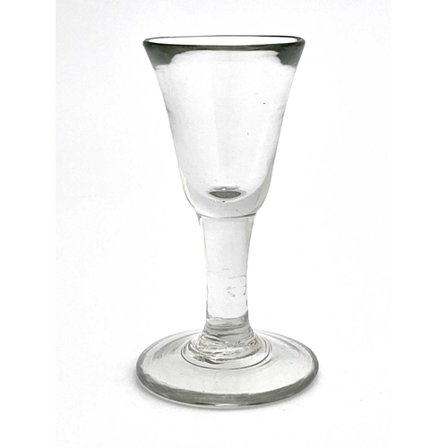 524 - A plain stemmed toasting glass, circa 1740, the heavy bell shaped bowl on a short stem and thick foo... 