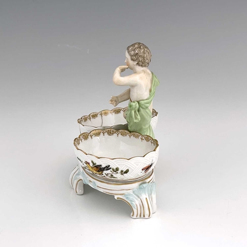 680 - A Berlin porcelain figural double salt cellar, 19th century, the central putto between two basket mo... 