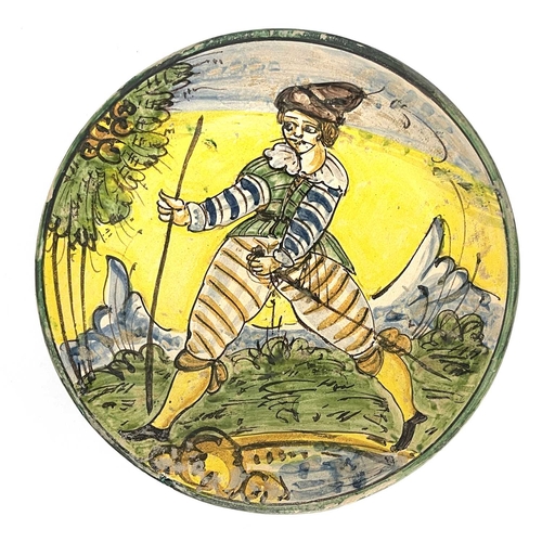 693 - A Montelupo dish, decorated in a typical palette depicting a male figure with sabre and walking staf... 