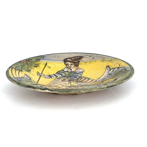 693 - A Montelupo dish, decorated in a typical palette depicting a male figure with sabre and walking staf... 