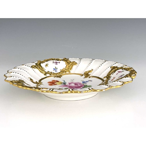 695 - A Meissen dish, relief moulded foliate scroll cartouches highlighted in gilt, with central floral bo... 