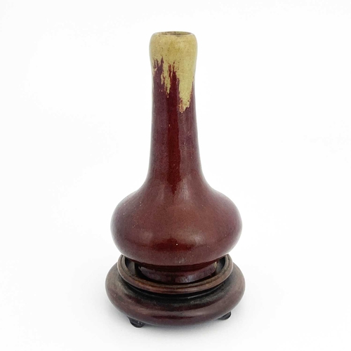 153 - A Chinese sang de boeuf glazed pottery vase, bulbous form, hares fur ochre over red glaze, on a wood... 