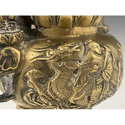 212 - An Oriental bronze censer, modelled in relief with a figure on a dragon to each side, the lid with G... 