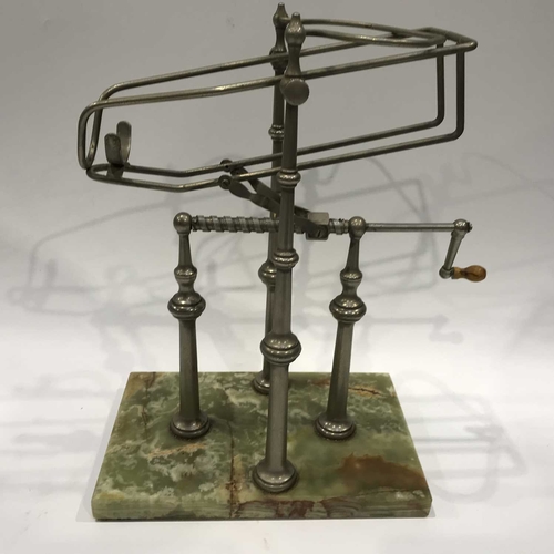 245 - A metal wine decanting cradle, corkscrew winding mechanism with wooden handle, on four knopped pilla... 