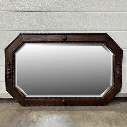 707 - An octagonal mirror, beaded wooden frame, with a bevelled edge. 82 x 52 cm