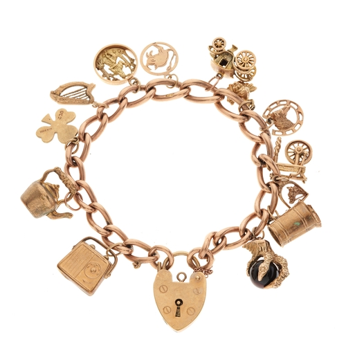 43 - A 9ct gold charm bracelet, suspending a series of period and later charms, with 9ct gold heart-shape... 